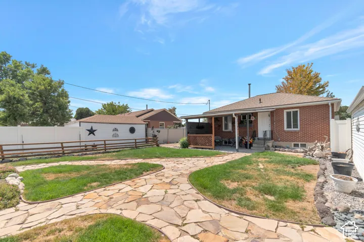 Brick exterior with covered patio, flagstone pathway, and white privacy fencing