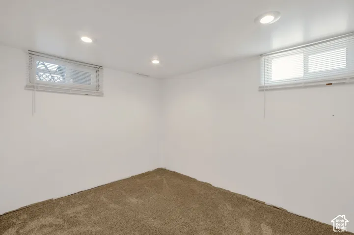 Neutral wall color with recessed lighting, two windows with blinds, and carpeted flooring