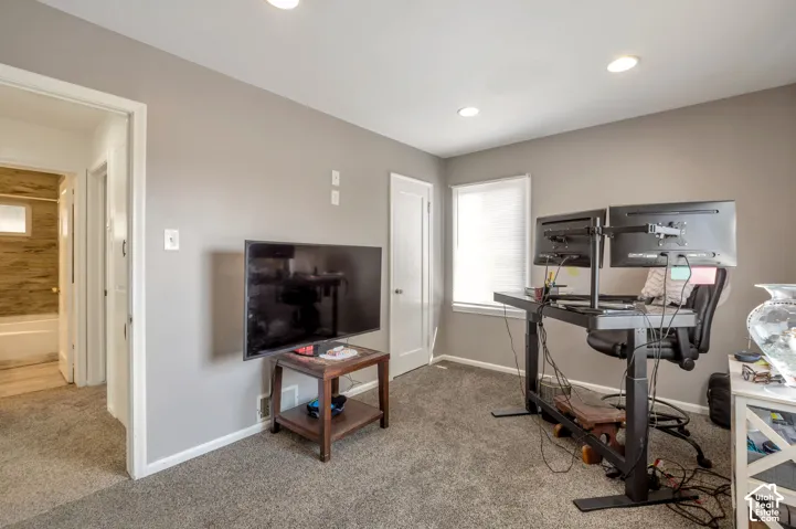 Recessed ceiling lighting, neutral wall paint, carpeted flooring, window with roller shade, and white trim throughout