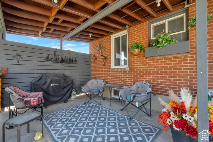 Covered patio area featuring a brick exterior wall and a slatted privacy fence. Great for entertaining guests in the heat. Totally covered.