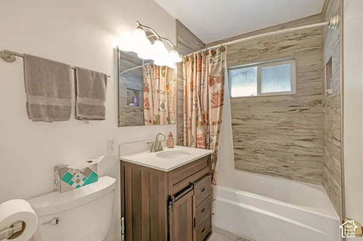Totally updated.Bathroom featuring a wood-finish vanity, white countertop, integrated sink, and an undermount tub with tiled surround