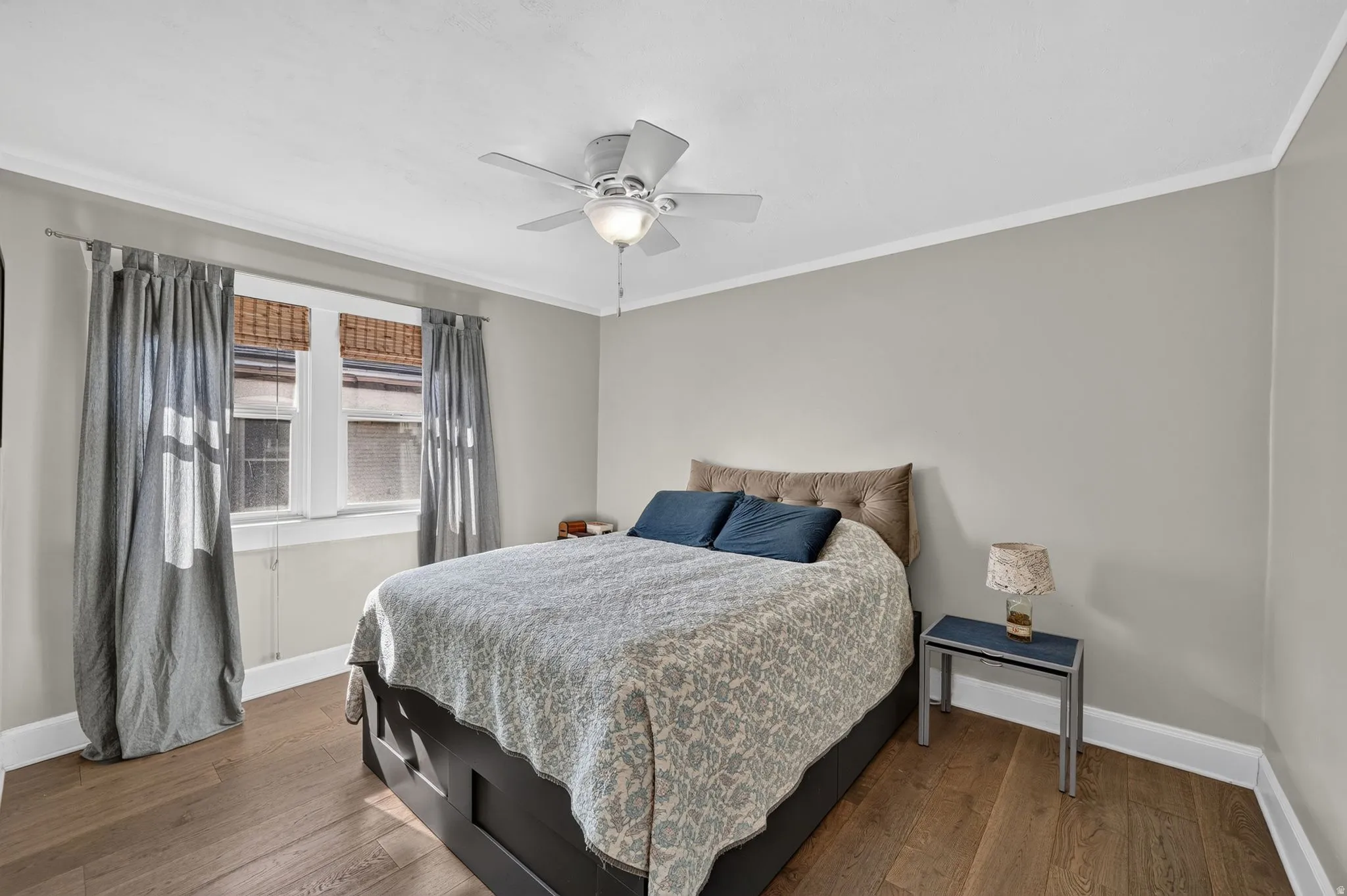 Hardwood-style flooring, white crown molding, ceiling fan with integrated lighting, two windows with blinds