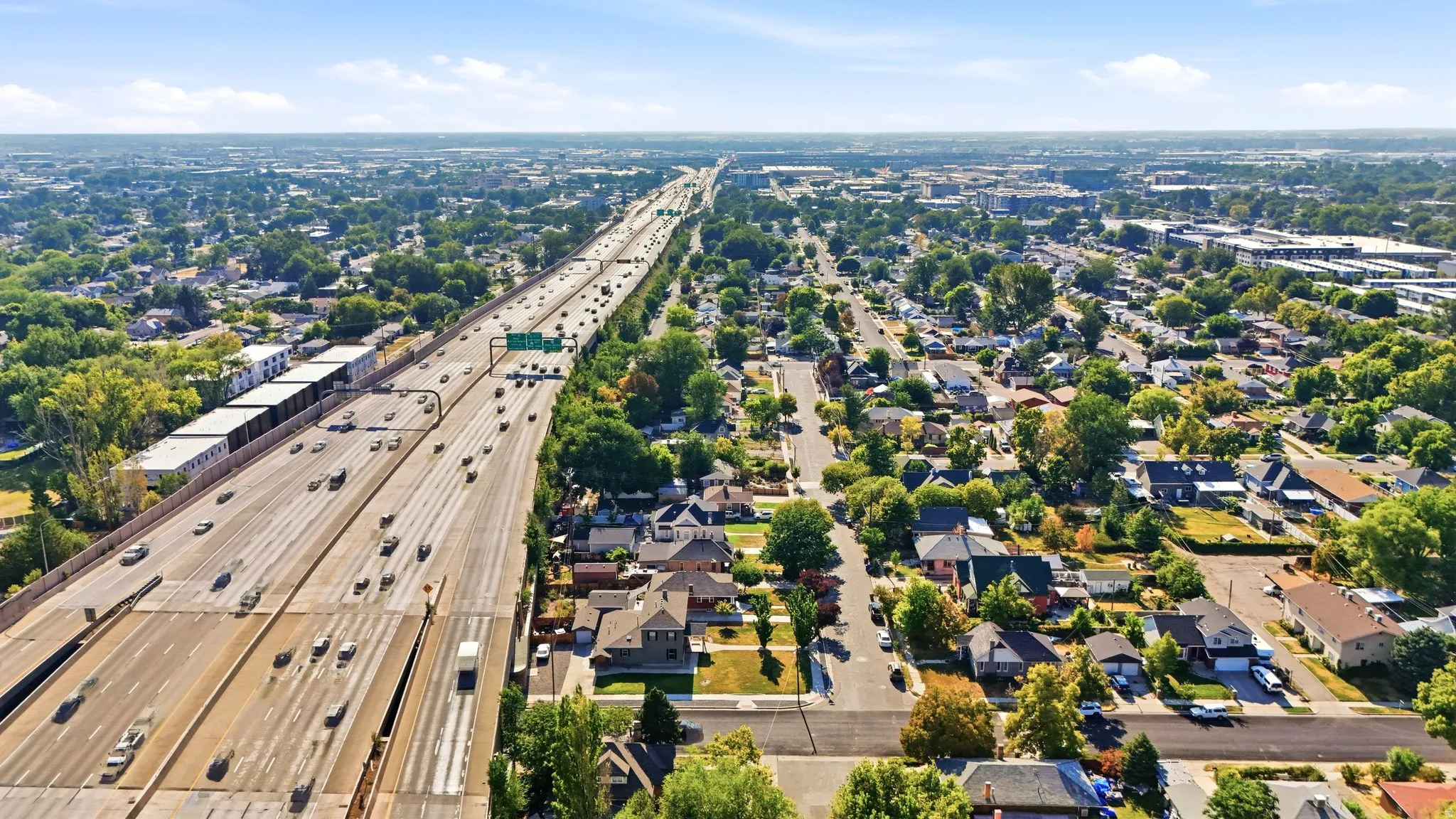 Expansive urban landscape featuring a multi-lane highway, residential areas, and commercial buildings