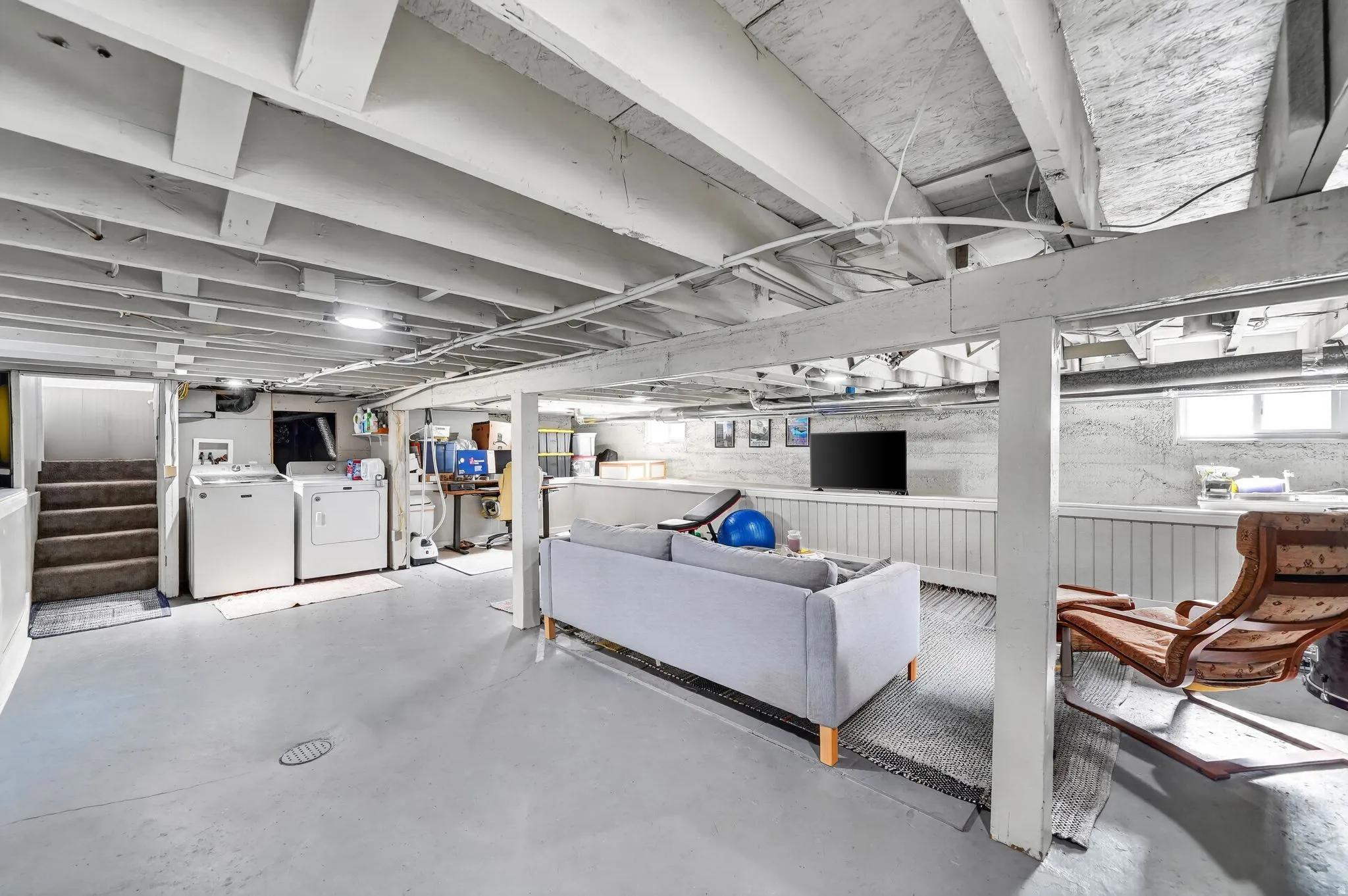 Finished lower level with painted exposed joists, concrete flooring, laundry area, and multiple windows