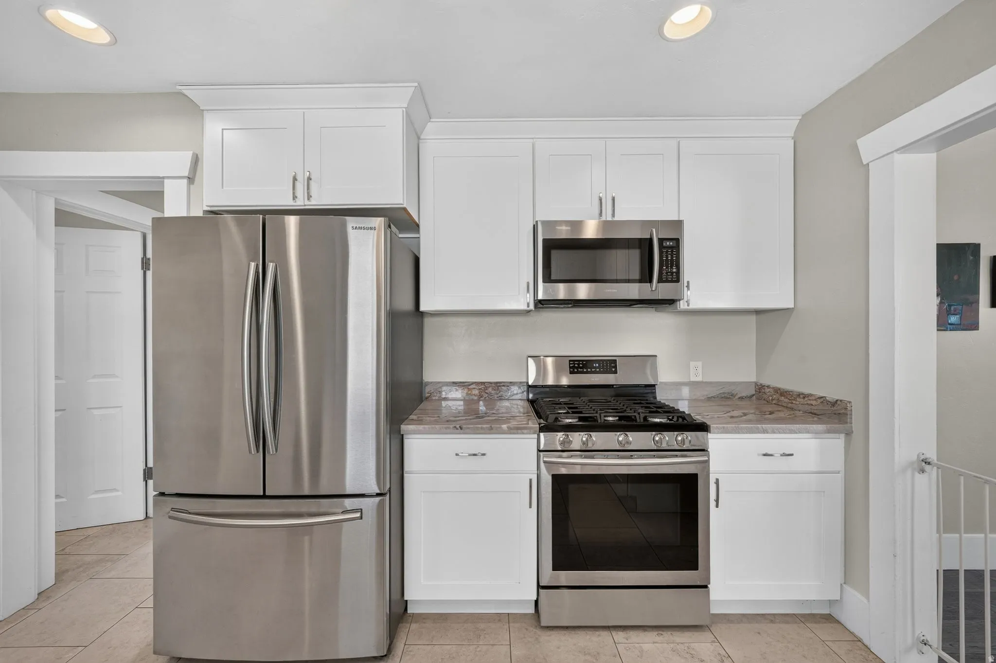 Kitchen featuring white shaker cabinetry, stainless steel appliances, solid surface countertops, and recessed lighting