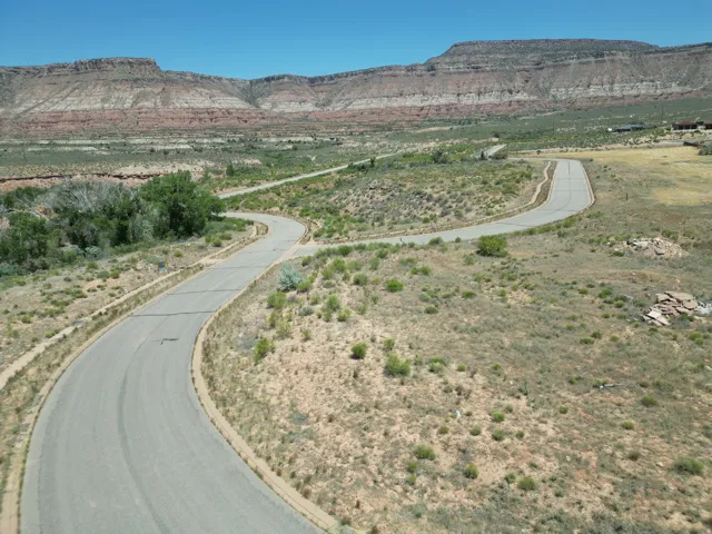 Paved road winding through expansive, natural landscaping with distant mountains