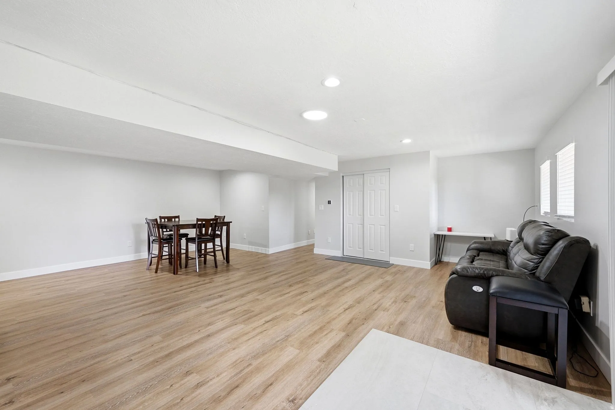 Expansive open-concept room featuring wood-finish flooring, recessed lighting, and bright white walls