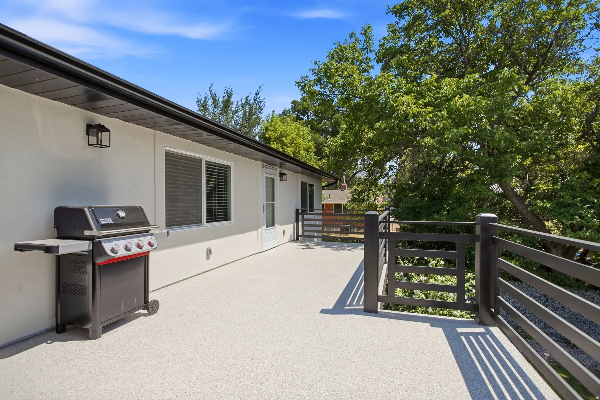 Spacious outdoor deck featuring light-colored surfacing and dark railing