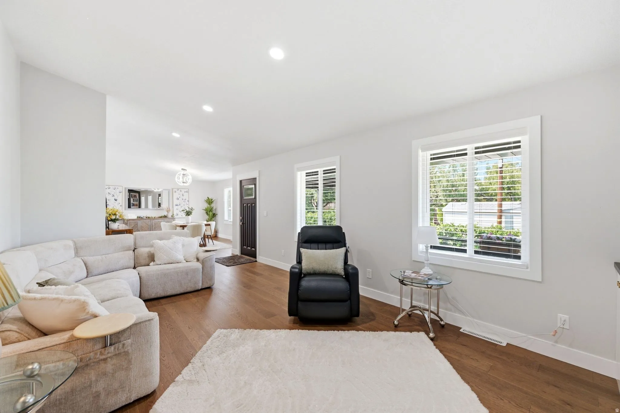 Vaulted ceilings with recessed lighting, wood-finish flooring, white window frames, and a dark-paneled entry door