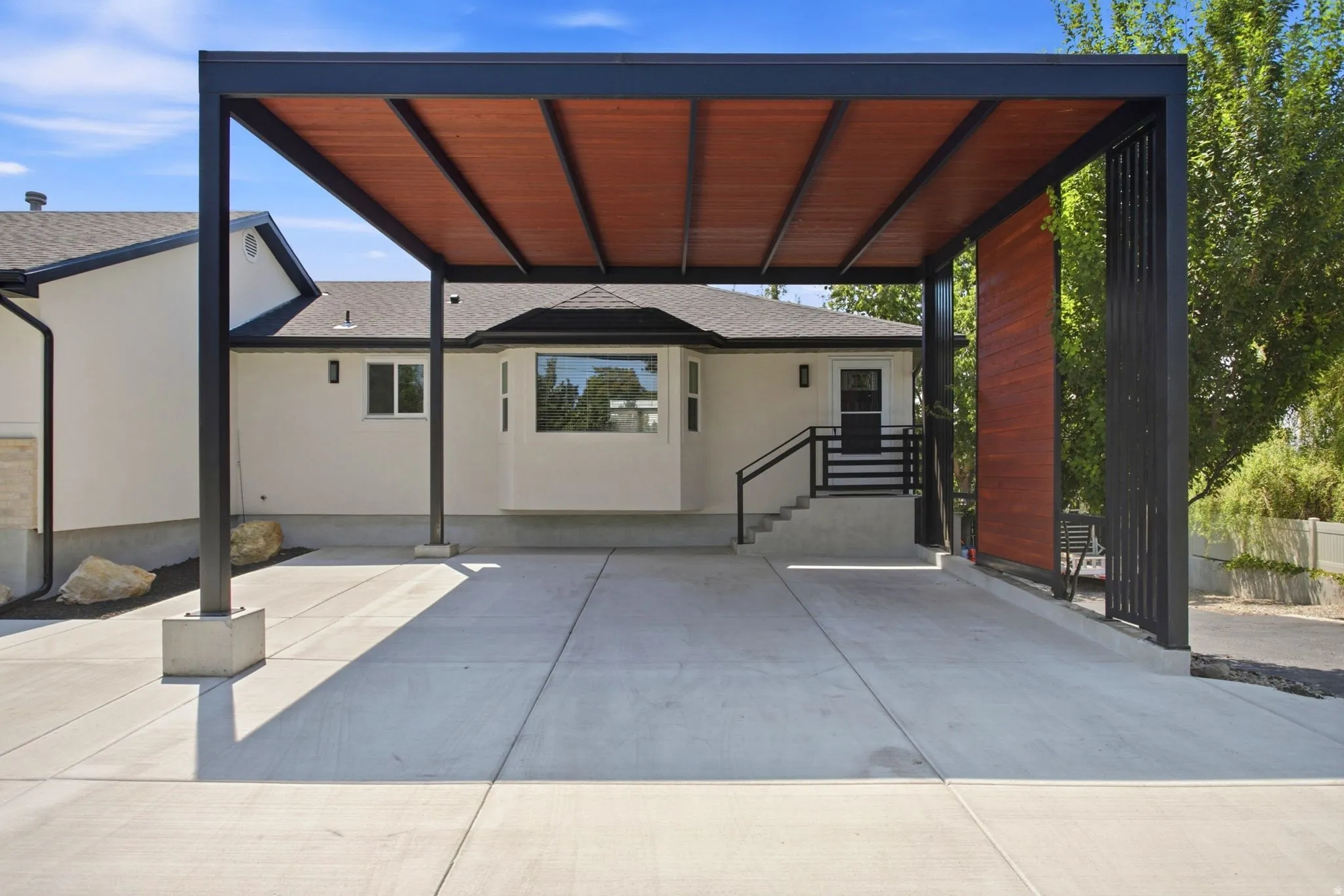 Modern carport with a wood-slatted roof and black metal framing
