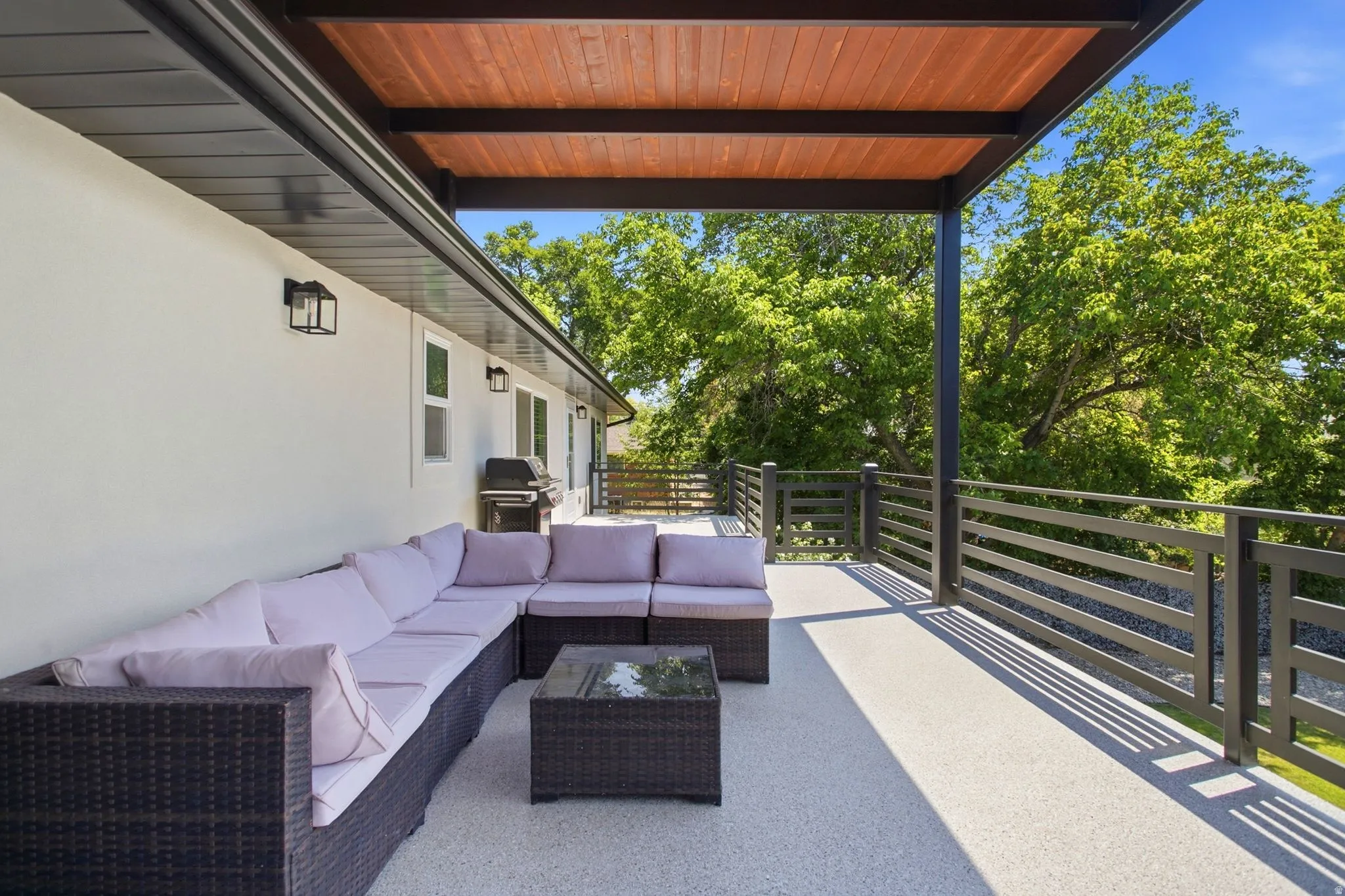 Spacious outdoor deck featuring a wood-finish ceiling, black metal railing, and recessed lighting