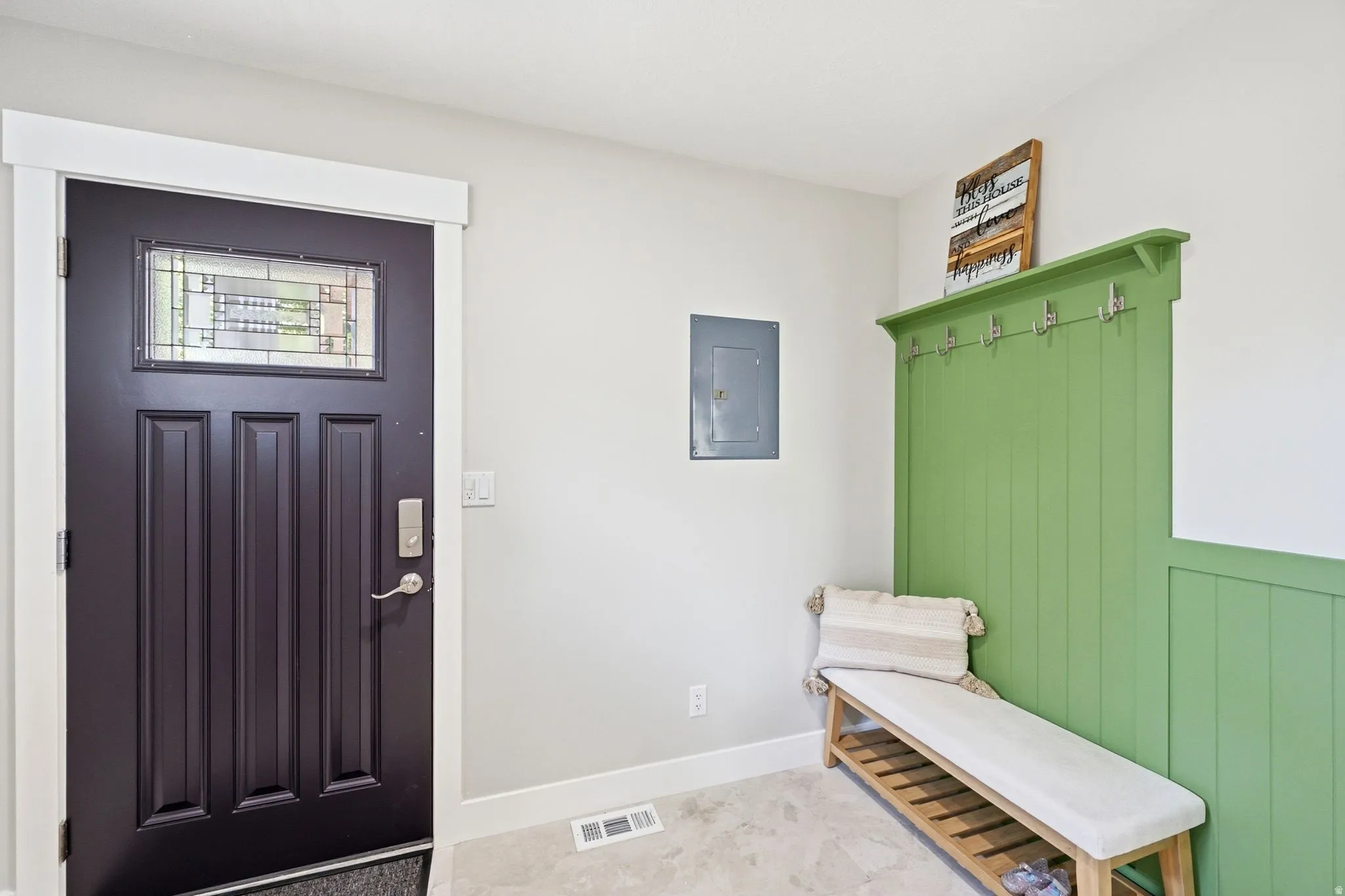 Entryway featuring a dark paneled door with decorative glass, a built-in green accent wall with coat hooks, and a built-in bench