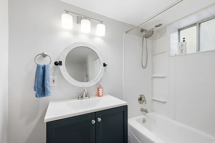 White bathroom with a dark-finish vanity, white countertop, and integrated sink