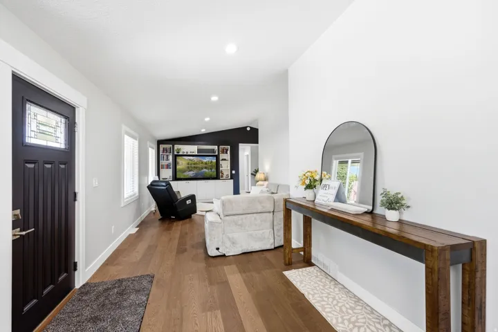 Rich wood-finish flooring, recessed lighting, white trim, custom built-in cabinetry, and a decorative front entry door with leaded glass