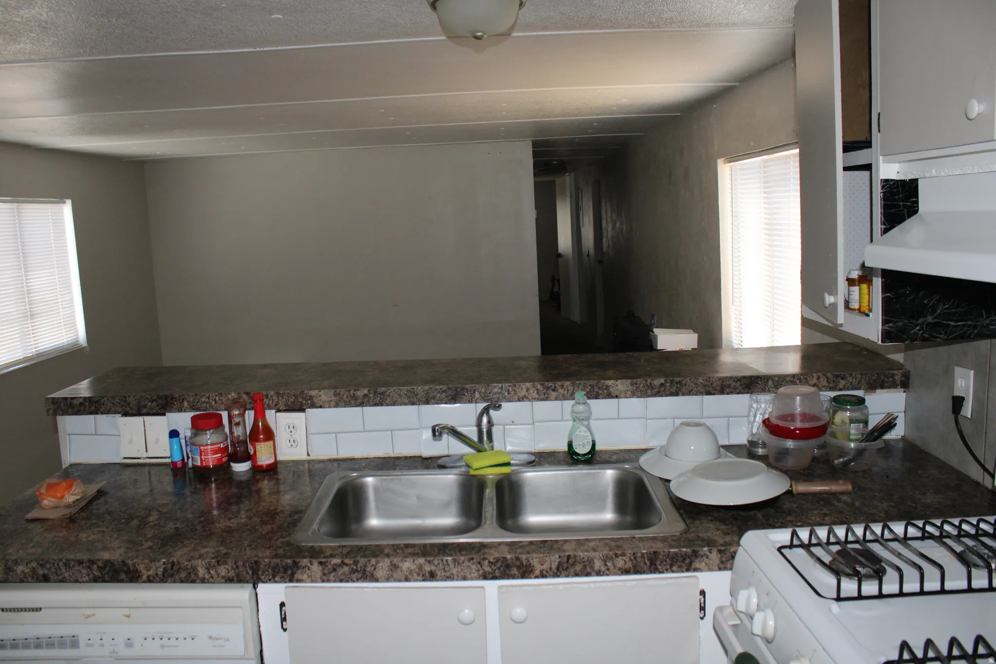 Kitchen with dual basin stainless steel sink, tile backsplash, and overhead cabinetry