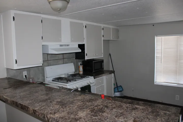 Kitchen featuring a gas range, tile backsplash, laminate countertops, and built-in cabinetry