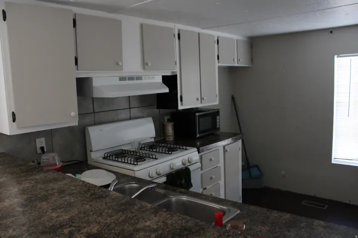 Kitchen featuring white cabinetry, a gas range, a dual-basin sink, and ample countertop space