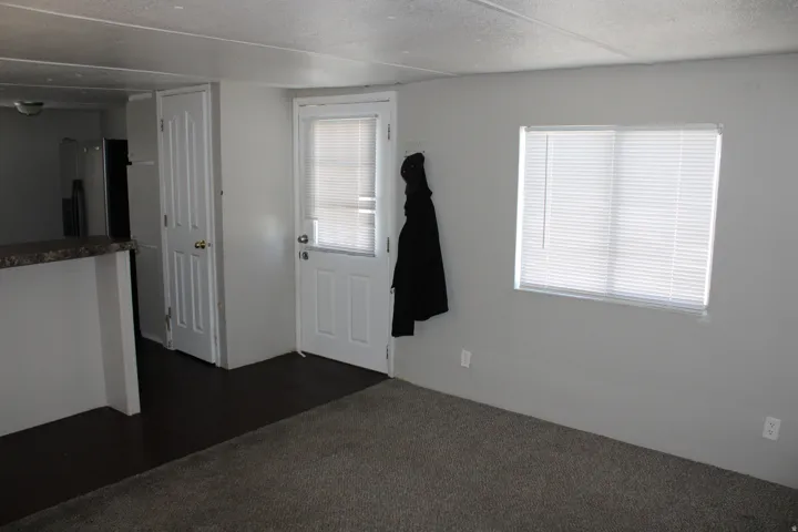 Carpeted flooring, window with blinds, interior door, exterior door with blinds, and a built-in counter