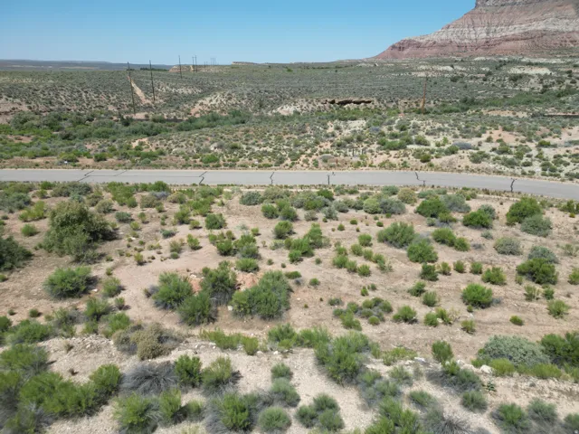 Paved road through a desert landscape with distant rock formations