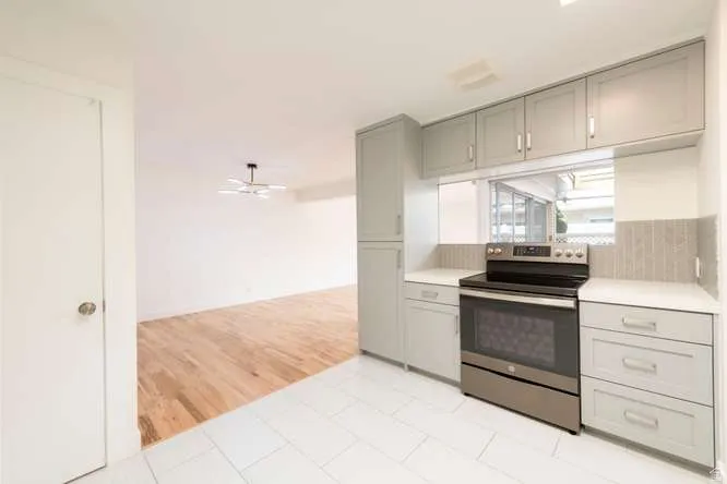 Kitchen featuring light gray cabinetry, stainless steel range, light-colored countertops, and a tiled backsplash