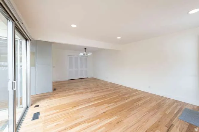 Hardwood-finish flooring, recessed lighting, sliding glass door, white bi-fold doors, and a decorative ceiling fixture
