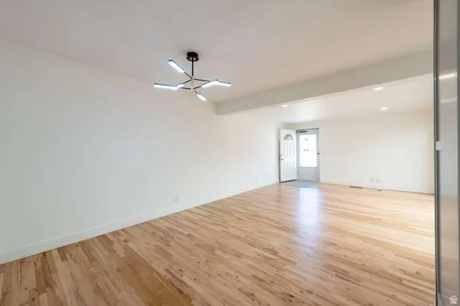 Expansive room with hardwood flooring, a modern multi-arm chandelier, and recessed lighting
