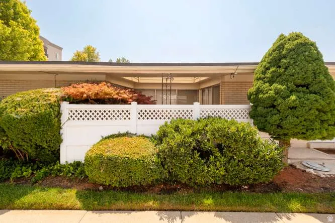 Manicured landscaping with mature shrubs and trees, complemented by a white lattice fence