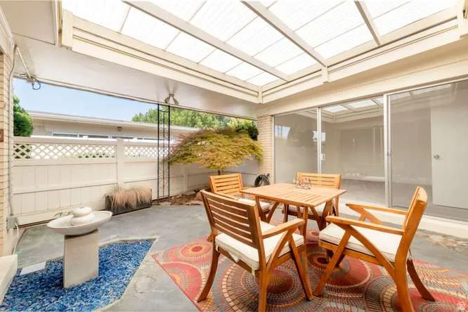 Covered patio featuring a translucent roof, concrete flooring, sliding glass doors, and a decorative privacy fence