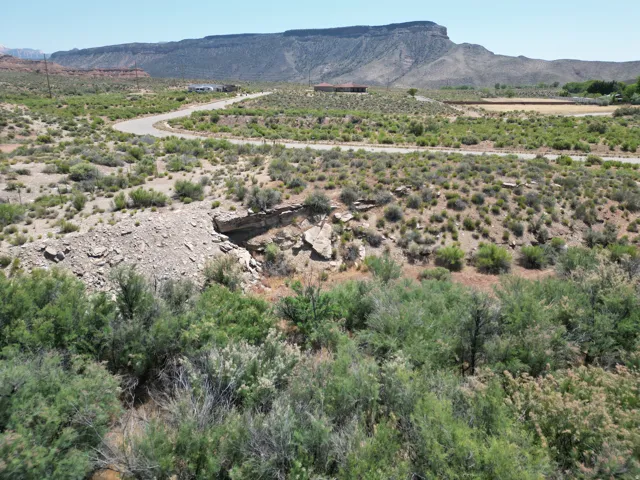 Expansive natural landscape featuring native scrub brush and a winding paved road