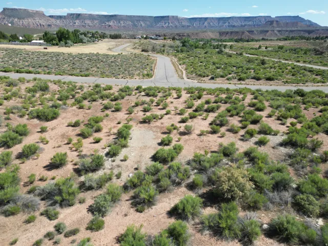 Expansive lot with desert landscaping, established road infrastructure, and distant mountain backdrops