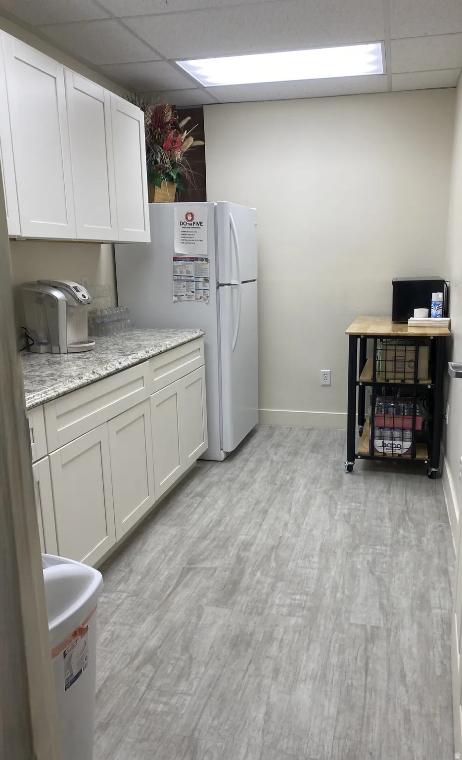 White cabinetry with brushed nickel hardware, granite-style countertops, wood-finish flooring, and recessed ceiling lighting