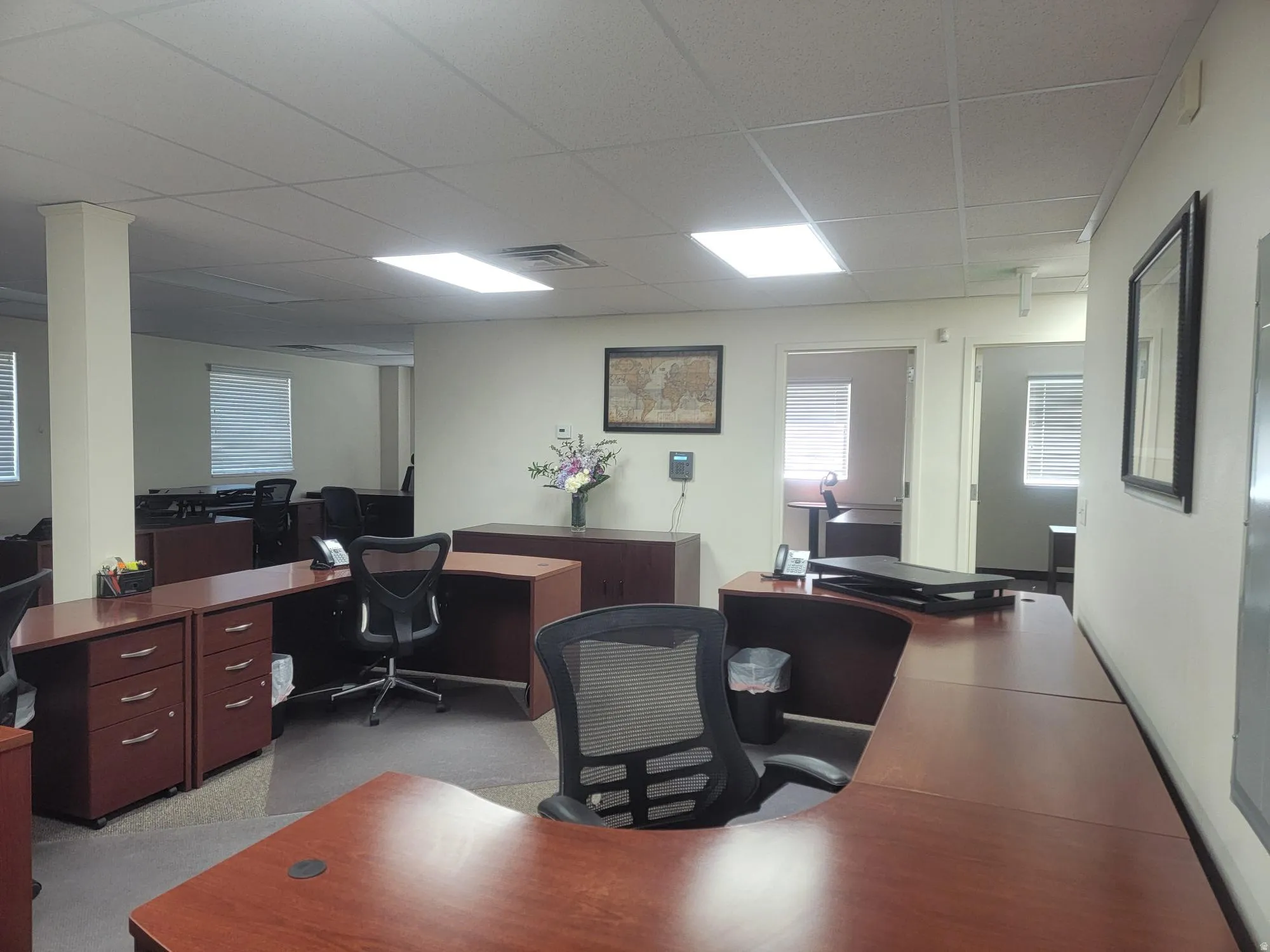 Open-concept office space with drop ceiling, recessed lighting, and individual offices featuring windows