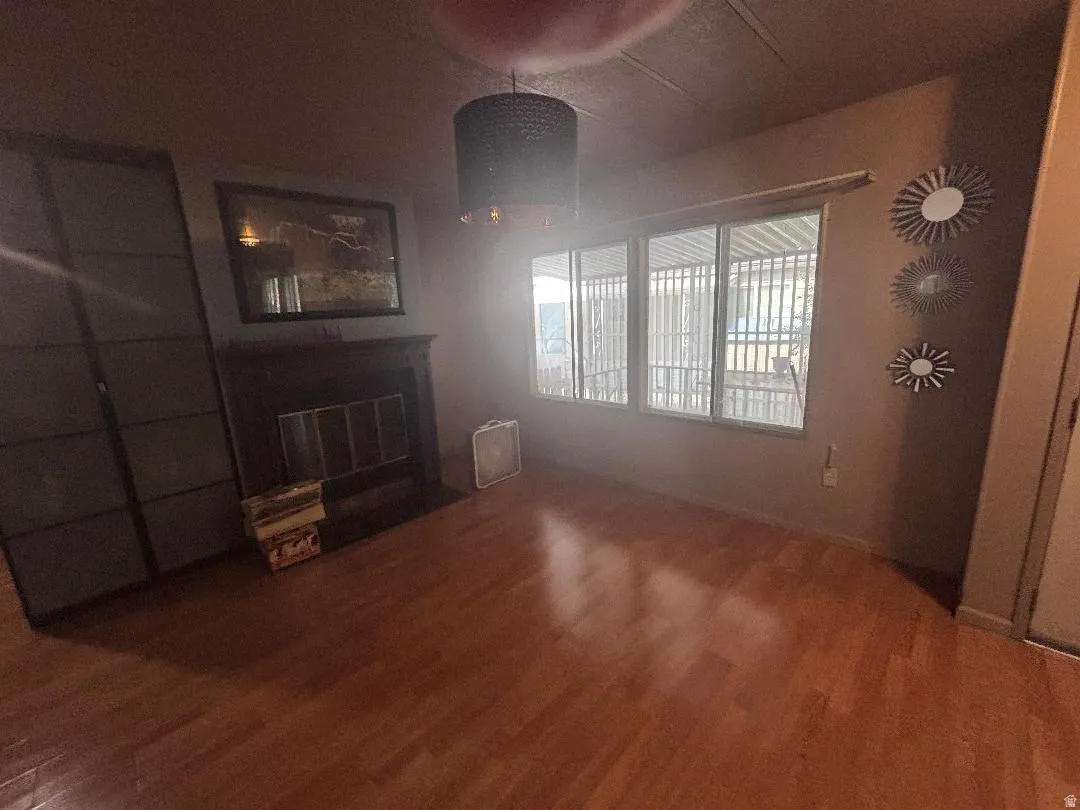 Wood-finish flooring throughout, featuring a dark-toned fireplace with a mantel, and a multi-pane window configuration