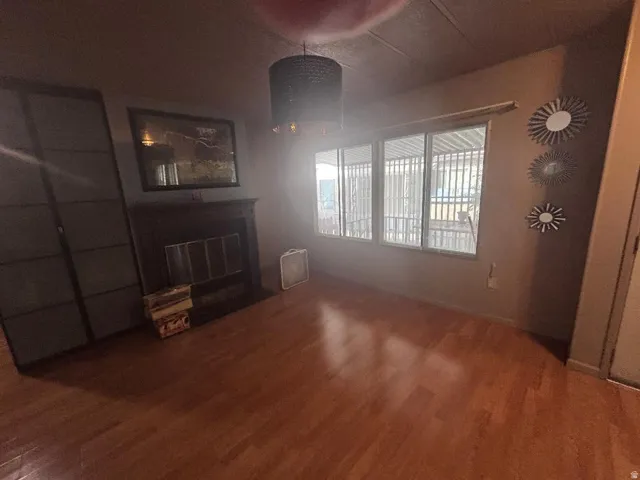 Wood-finish flooring throughout, featuring a dark-toned fireplace with a mantel, and a multi-pane window configuration