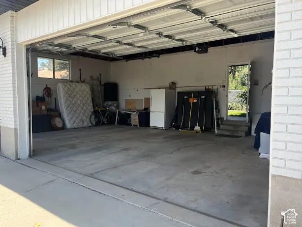 Attached garage featuring a concrete floor, an overhead door, and a side access door