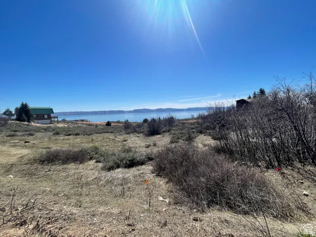 Expansive undeveloped land with a distant lake, distant mountain range, and a distant structure with a green roof