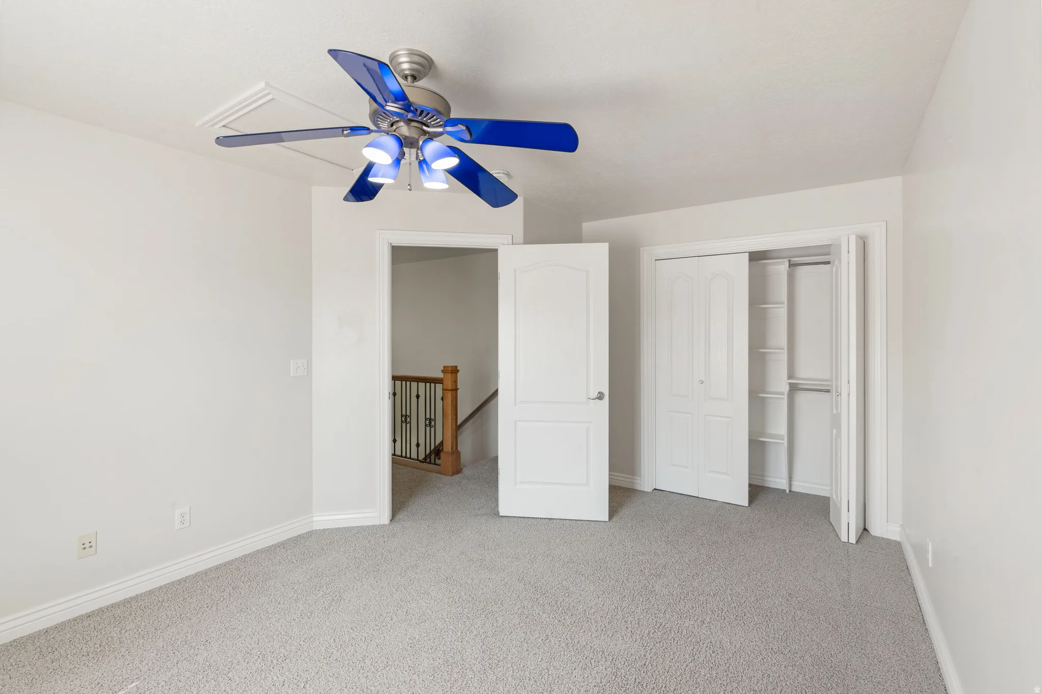 Plush gray carpeting, white painted walls, and a ceiling fan with light fixture