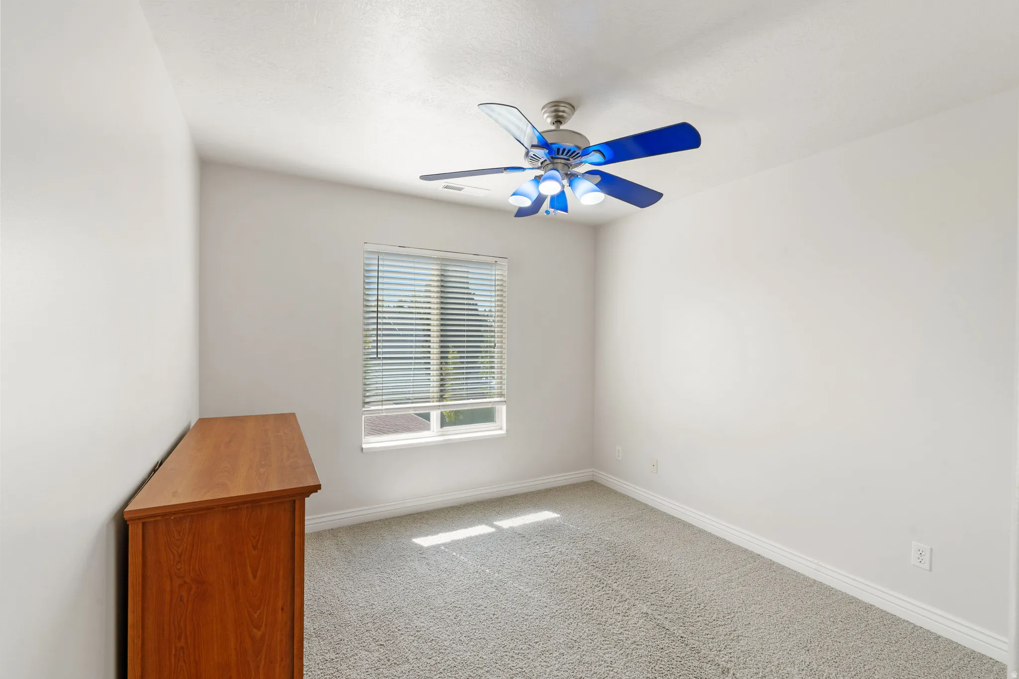 Carpeted flooring, window with horizontal blinds, and a ceiling fan with integrated lighting