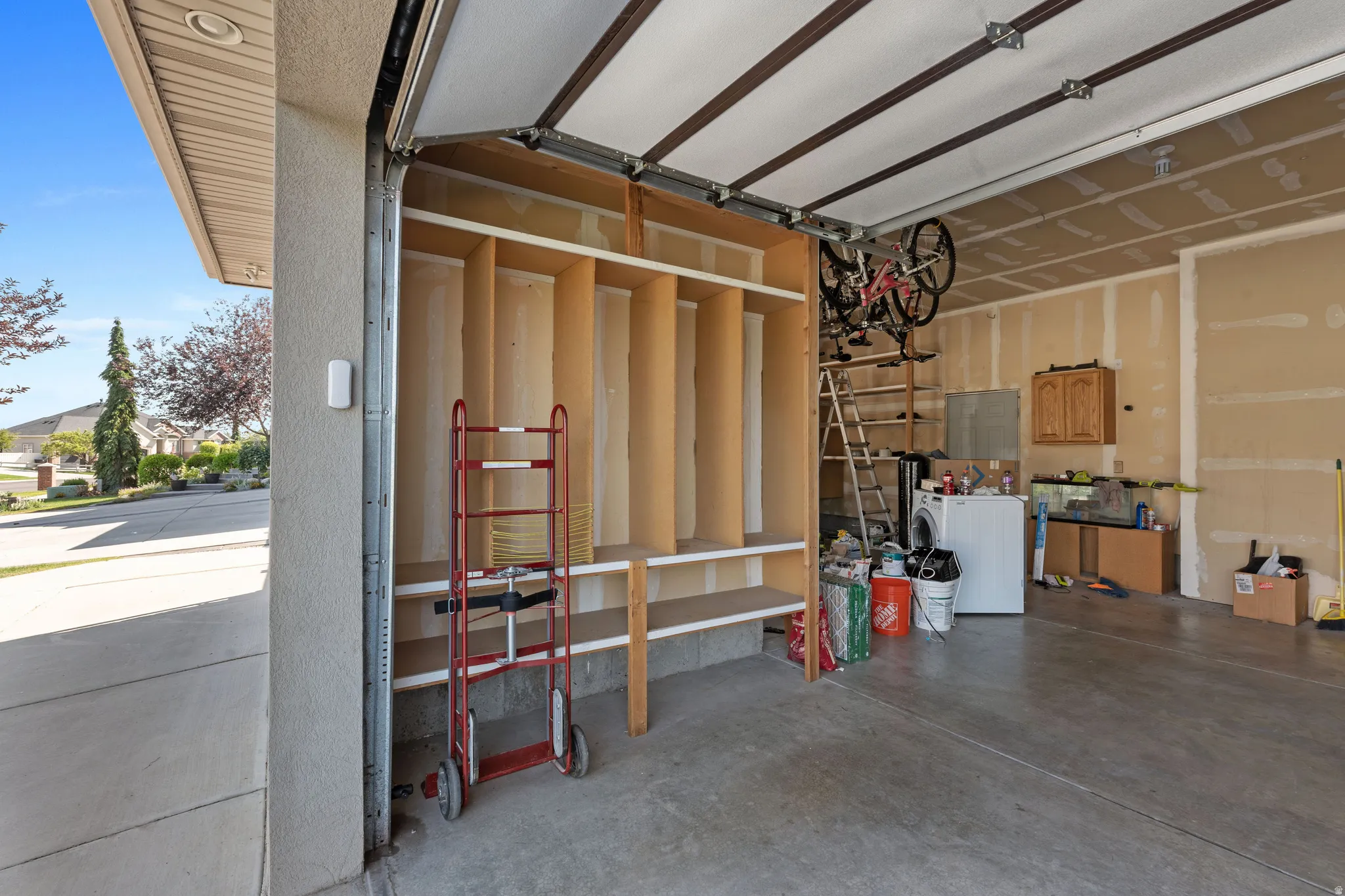 Garage with concrete flooring, built-in shelving, and overhead storage