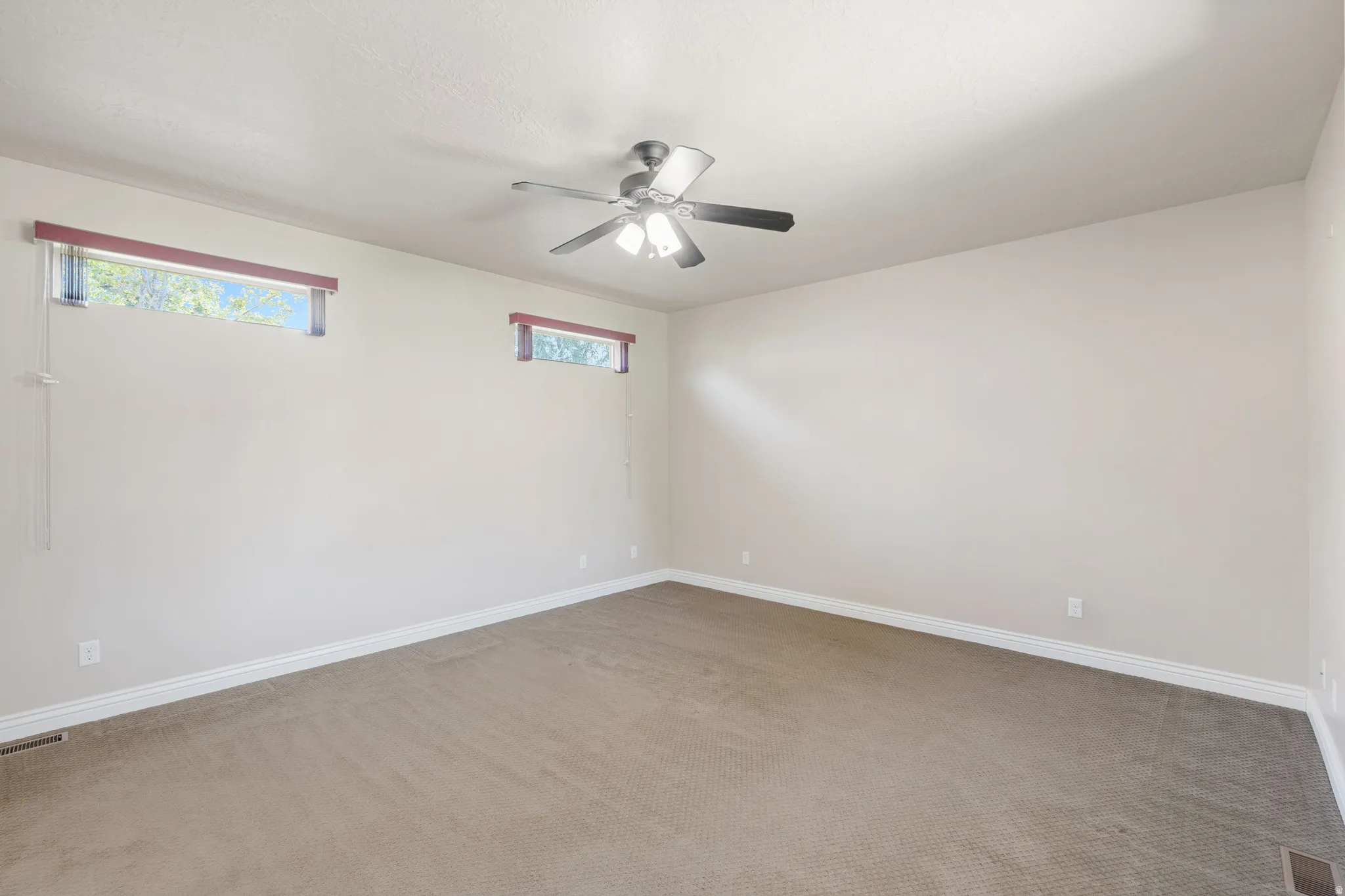 Recessed windows, ceiling fan with integrated lighting, and neutral carpet flooring