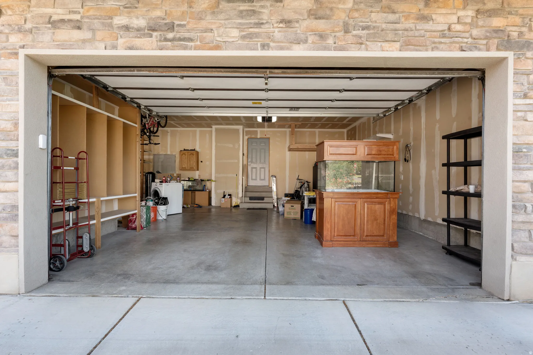 Stone-clad garage exterior with a concrete driveway and an automatic garage door