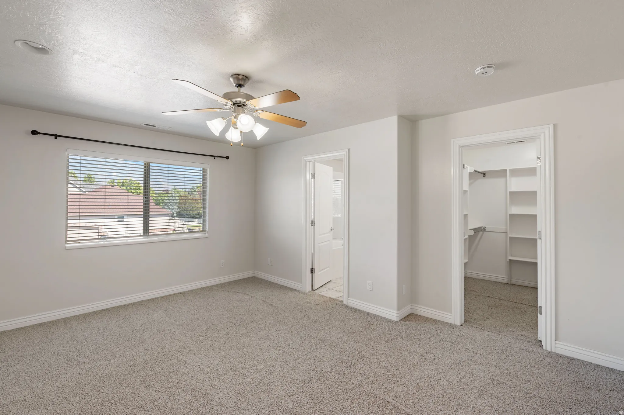 Recessed lighting, ceiling fan with light fixture, window with blinds, carpeted flooring, and built-in closet shelving