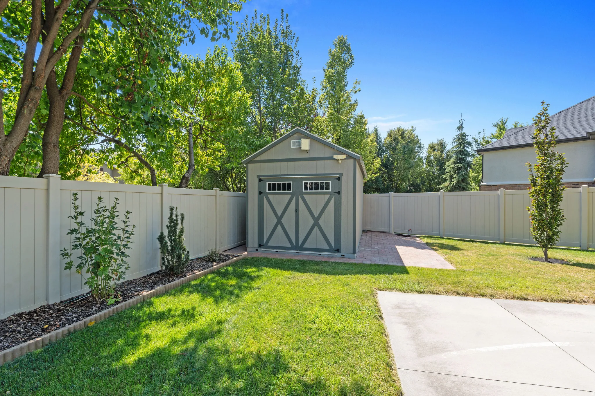 Manicured lawn with a detached storage shed, full privacy fencing, and a paved pathway