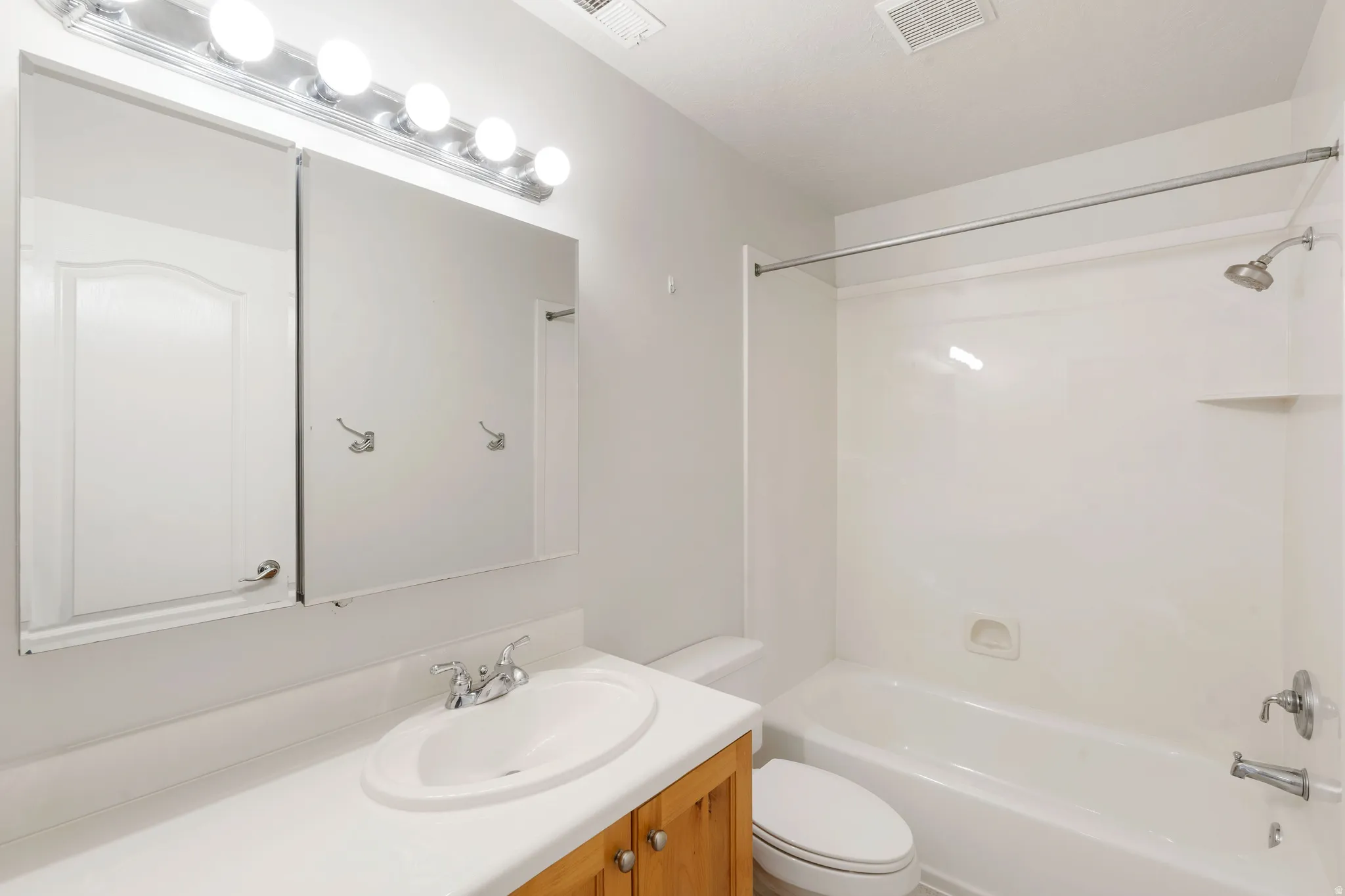 Vanity with wood-finish cabinetry, white countertop, and integrated sink