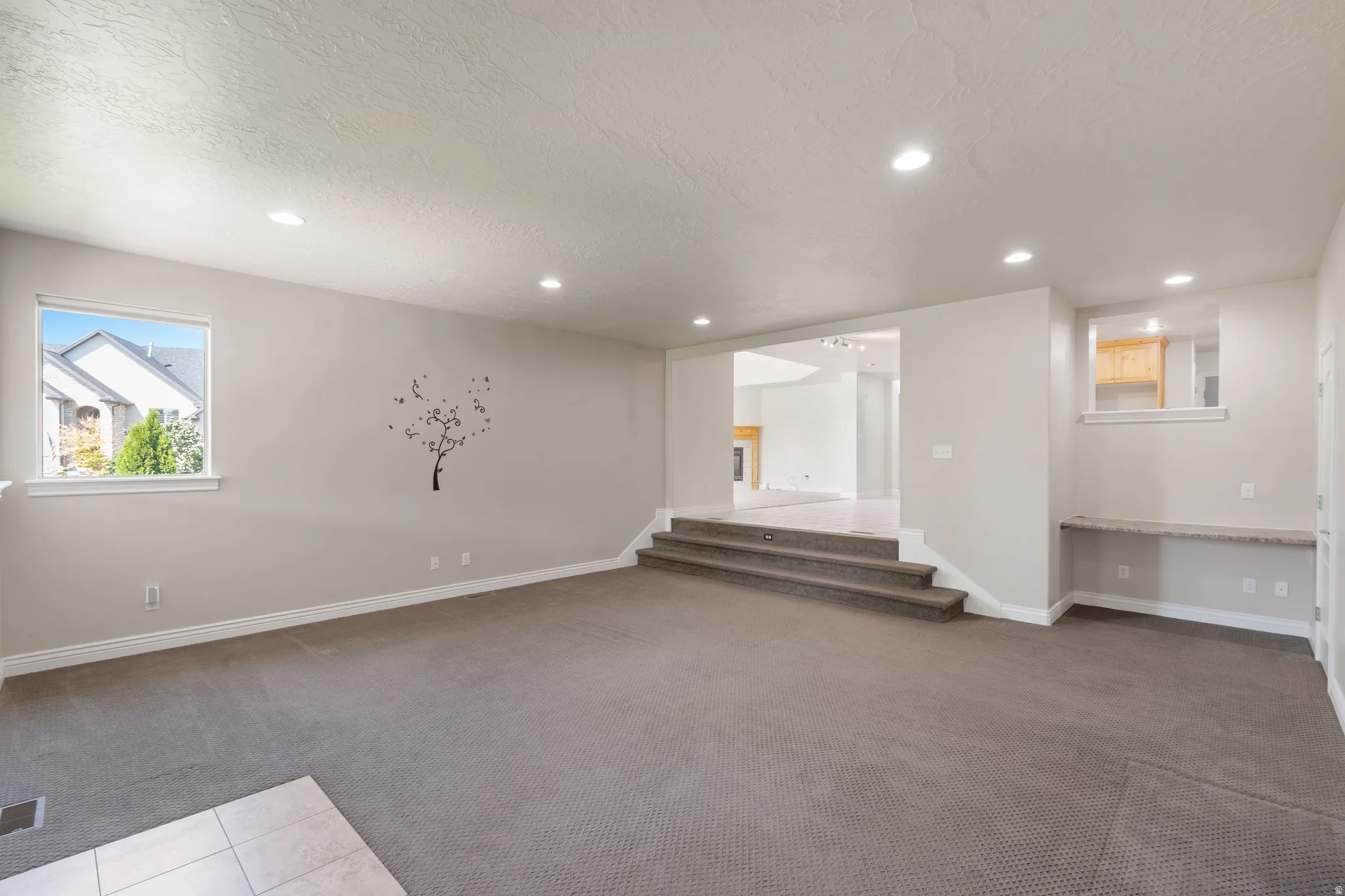 Spacious room with recessed lighting, light-toned walls, and neutral carpeting