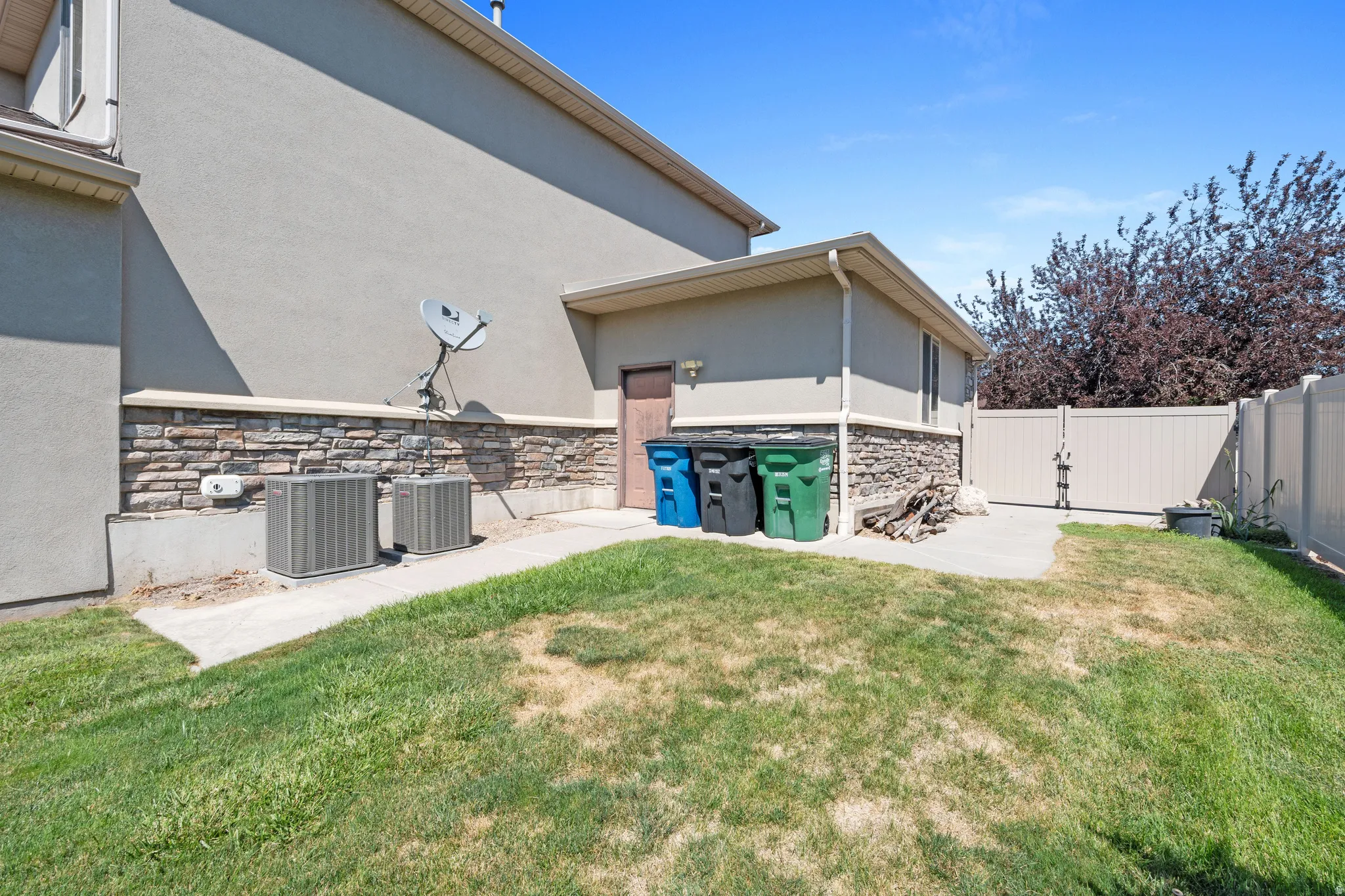 Spacious backyard with established lawn and mature landscaping, complemented by a stone-accented exterior, utility shed with storage, and fenced perimeter for privacy and security