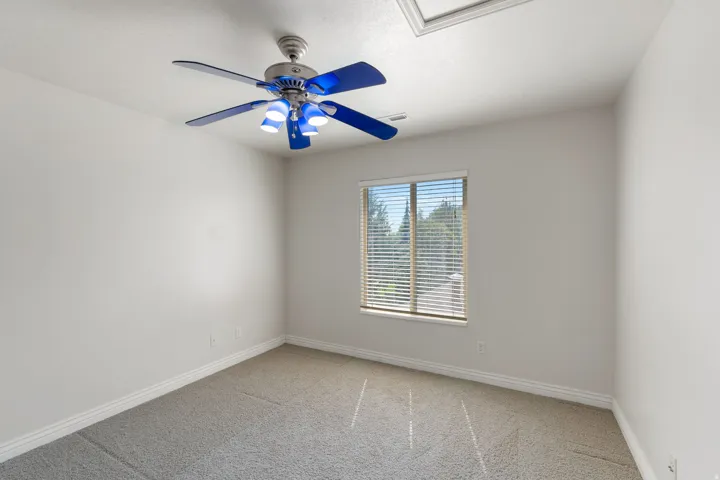 Neutral wall finishes, recessed window with blinds, ceiling-mounted fan with light fixture, and textured carpeting