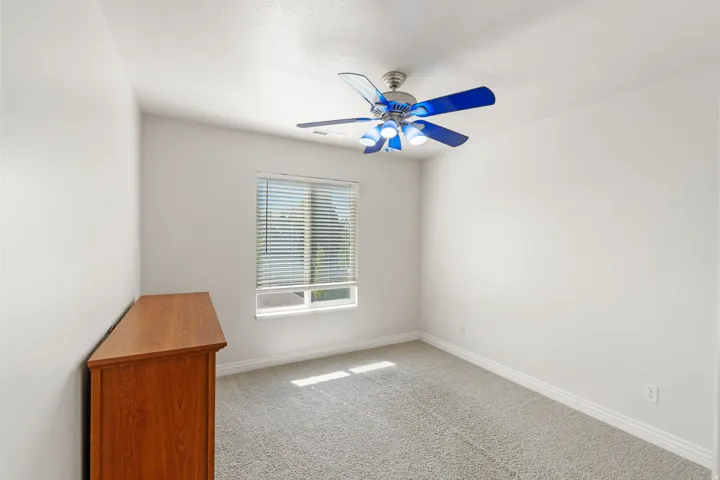Carpeted flooring, window with horizontal blinds, and a ceiling fan with integrated lighting