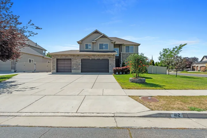 Two-story residence featuring stone and stucco exterior, a two-car garage, and a concrete driveway