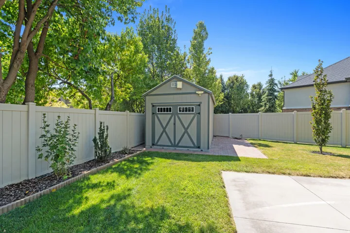 Manicured lawn with a detached storage shed, full privacy fencing, and a paved pathway